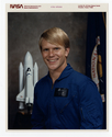 Portrait of astronaut candidate George D. Nelson in blue flight suit, 1978