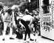 Taylor Mead and two unidentified people painting booth at 1966 Cassis Festival, with crowd watching